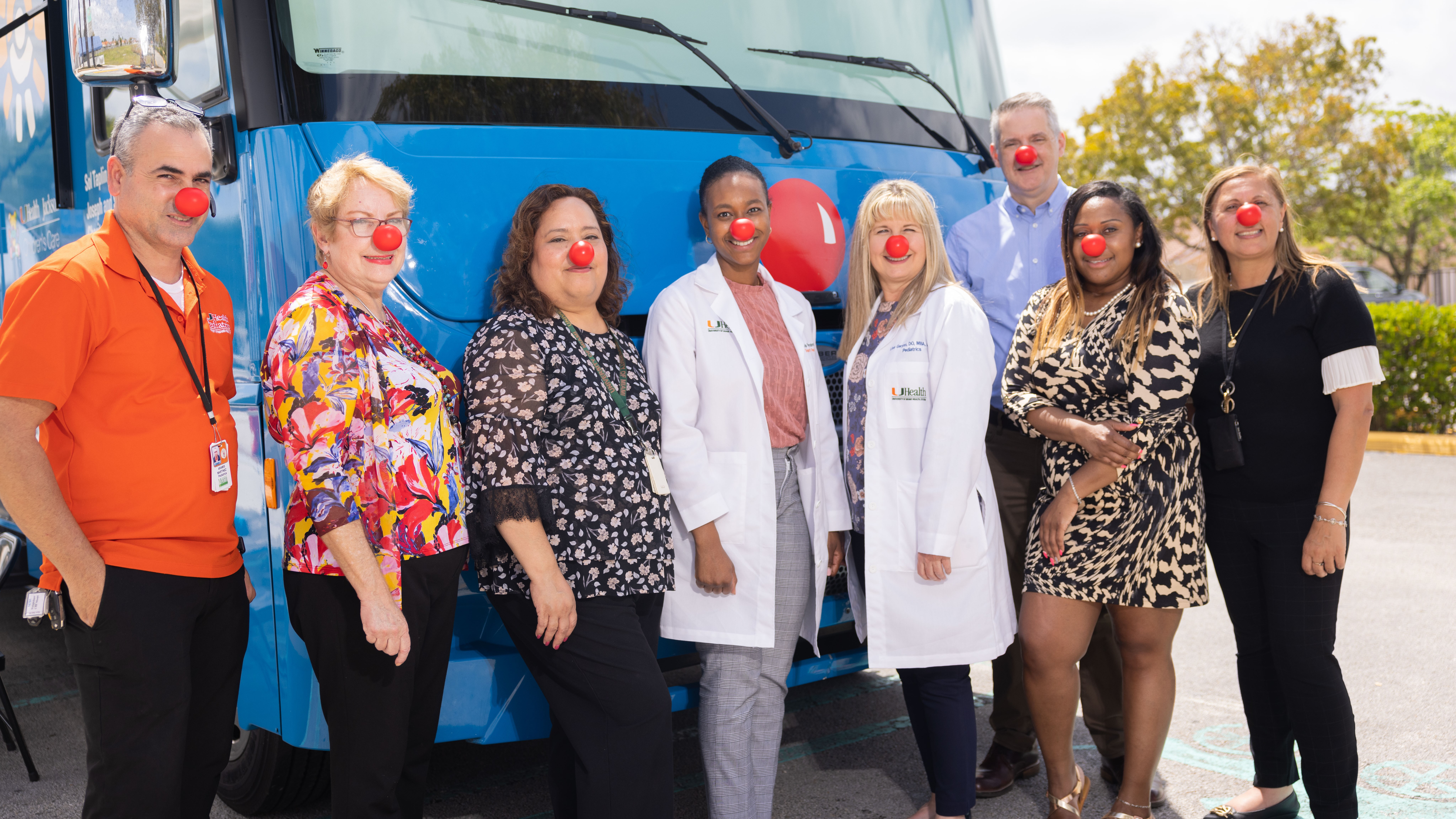 doctors with red noses in front of bus