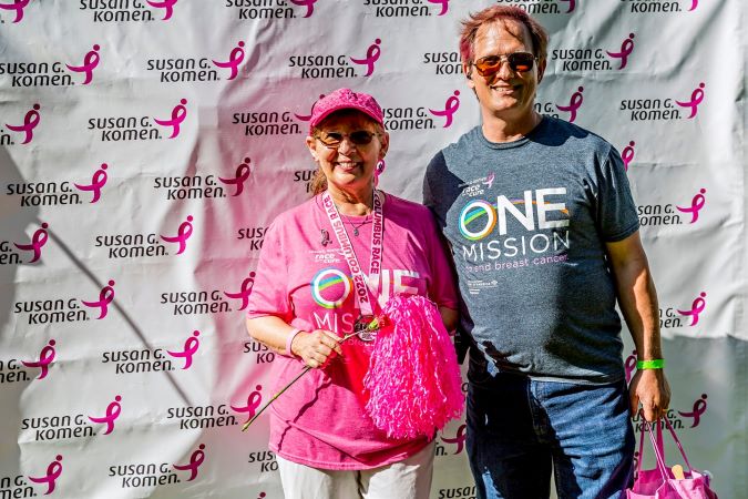 breast cancer race participant in pink clothing in front of susan g komen sign